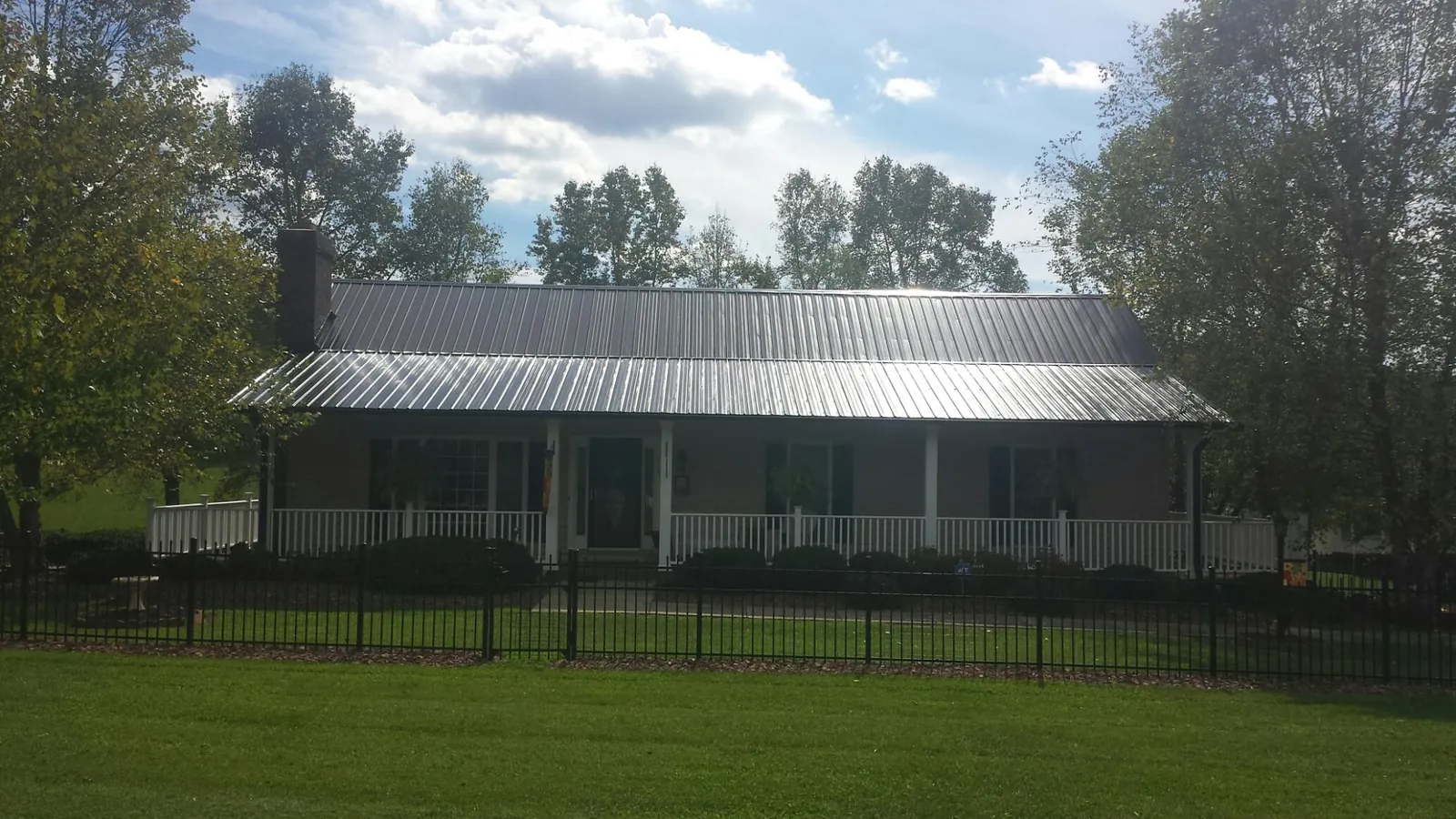 Gray metal roof on a brick ranch with a full width front porch — Gutter Guard Installation work by our crew in East Brunswick
