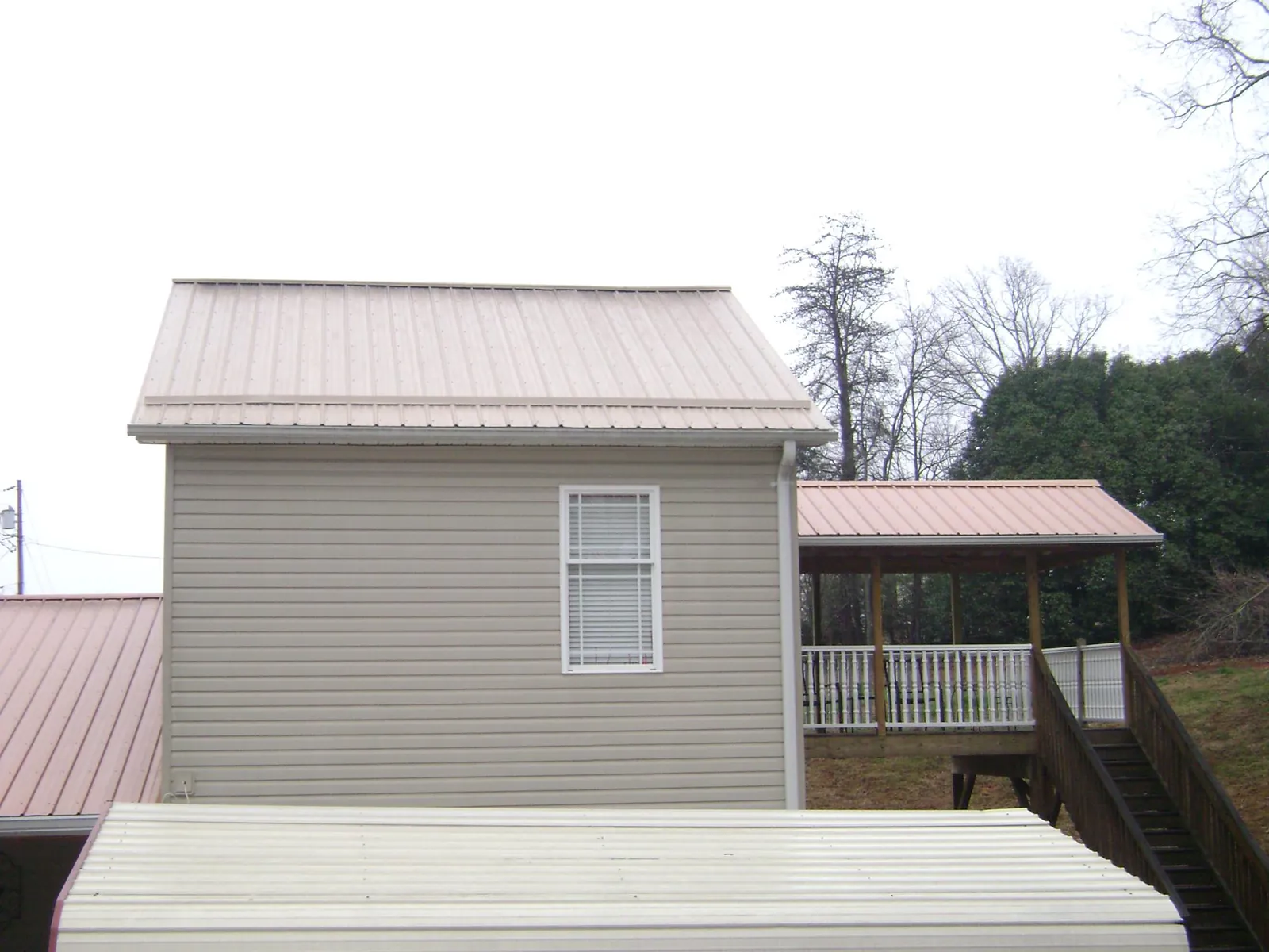 Tan metal roofs on a two story addition and attached porch, from a Roof Replacement job in East Brunswick