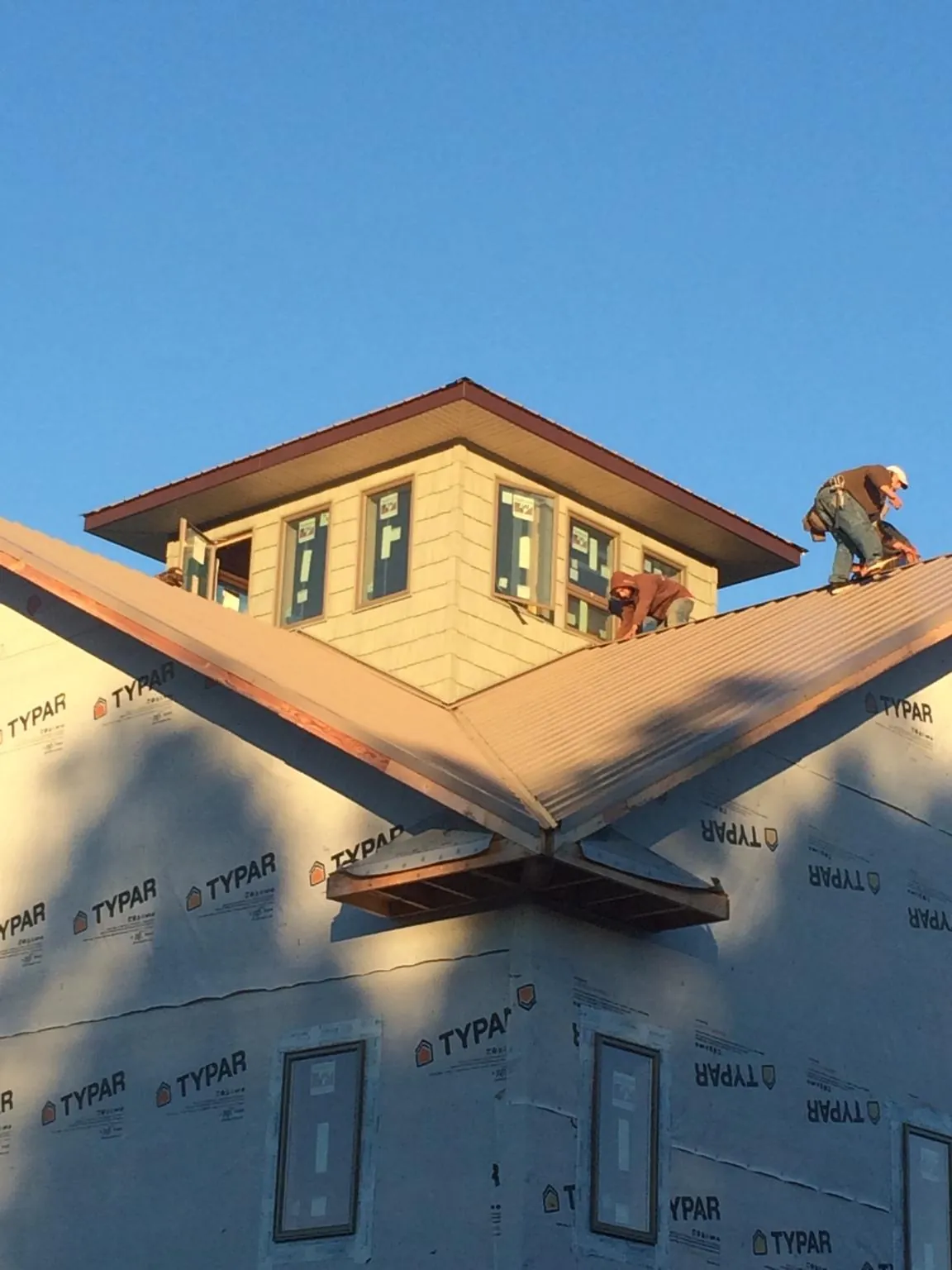 Roofers working around a rooftop cupola on a new metal roof at sunset — Roof Waterproofing in East Brunswick by Roofing Brothers